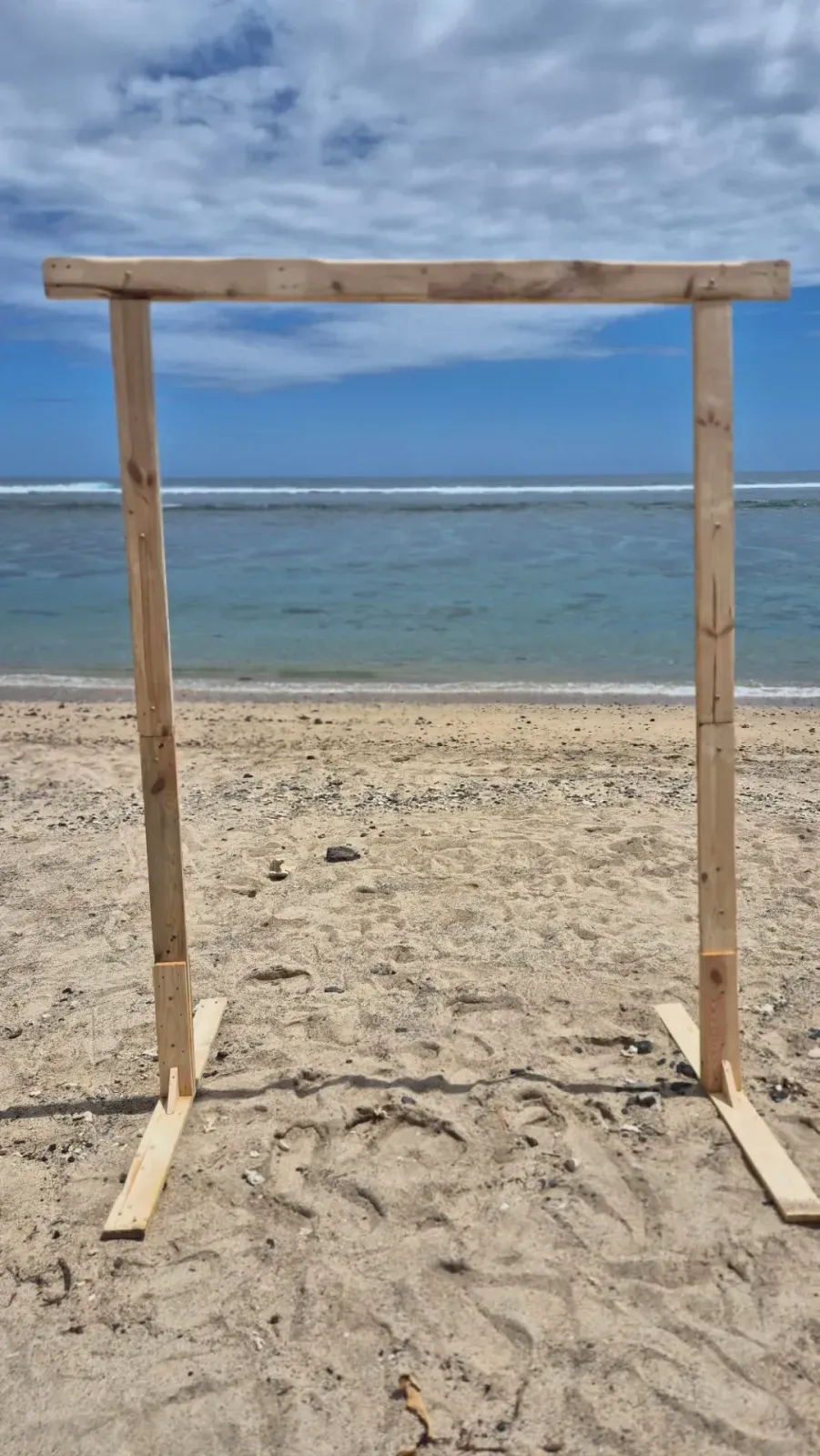 Arche rectangle en bois clair, sans décor, posée sur le sable face à l'océan