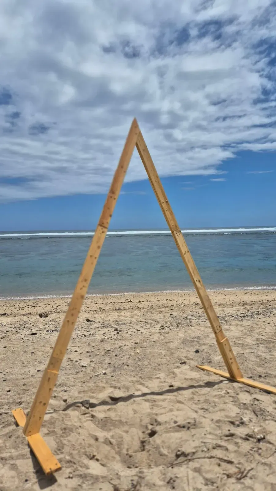 Arche triangle en bois de palette posée sur le sable face au lagon