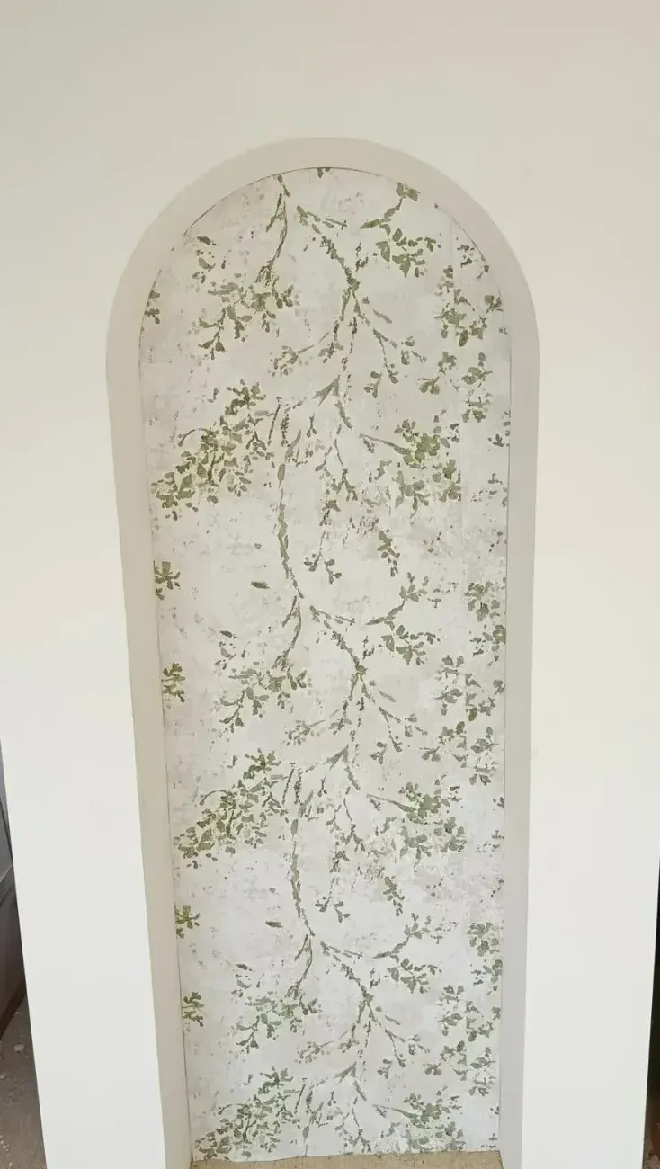 Panneau d'arche blanche arrondi à fond décoratif de feuillage, utilisé comme fond de cérémonie