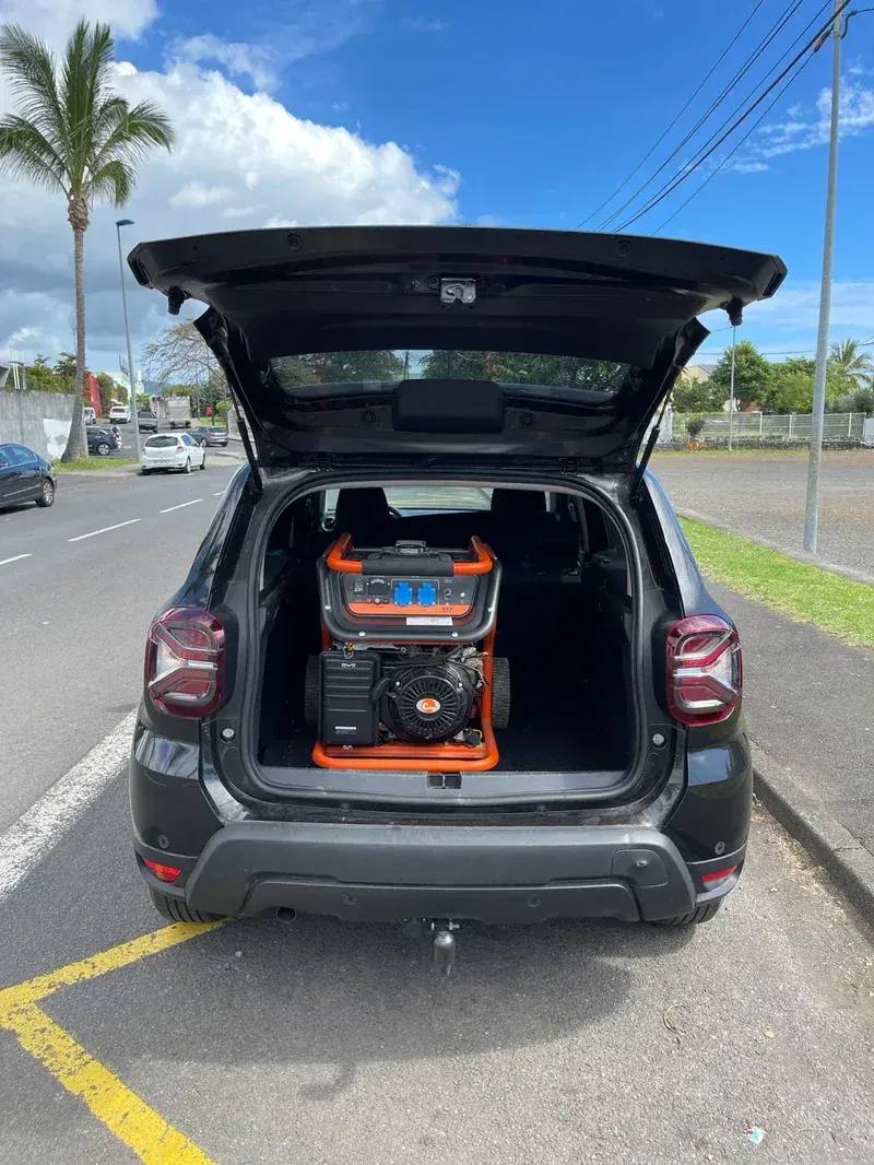 Groupe électrogène orange chargé dans le coffre d'un véhicule sur un parking de La Réunion