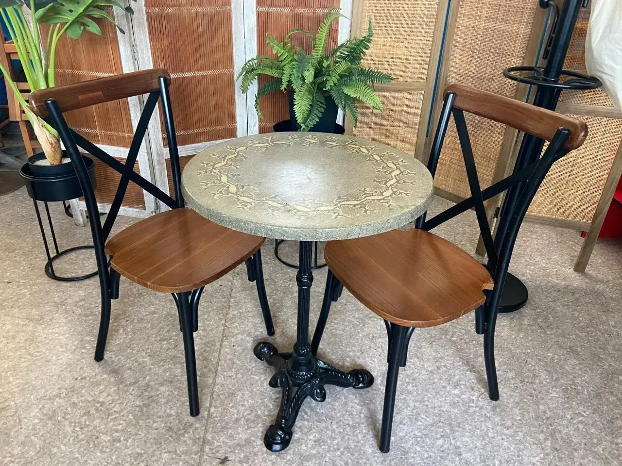 Table bistrot ronde en pierre claire et deux chaises en bois à dossier croisé